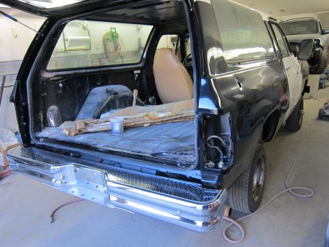 1987 Dodge 1500 - Rear view of a black SUV, likely a 1987 Dodge Ramcharger, in a repair shop with its tailgate open.