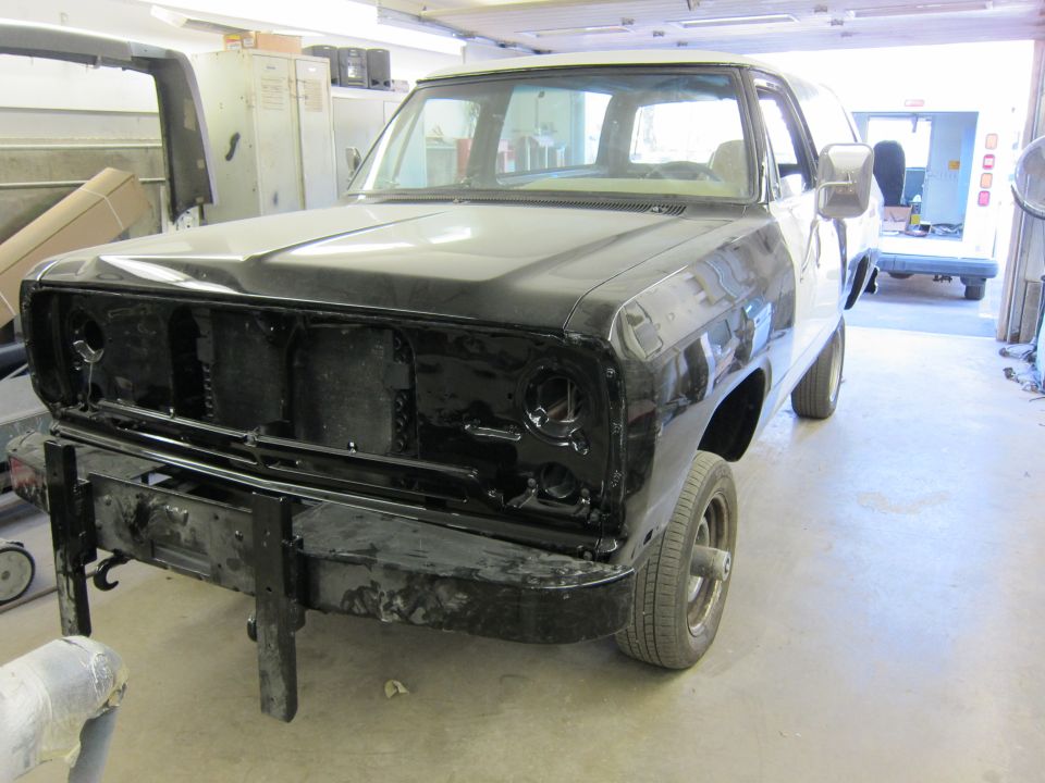 Front view of black pickup truck, undergoing bodywork. Visible grille and bumper removed