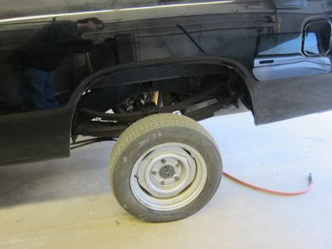 1987 Dodge 1500 - The rear wheel well of a black pickup truck is shown, with suspension components and a tire visible.