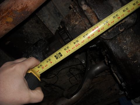 1979 Ford F-150 - Measuring undercarriage components with a tape measure. The exact vehicle is not identifiable.