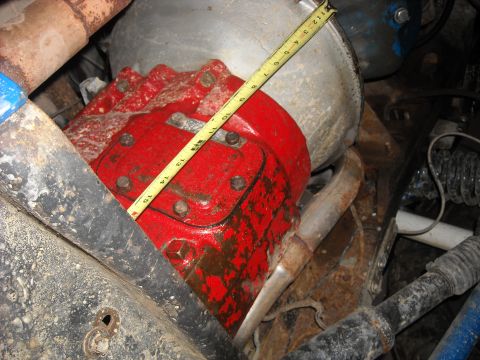 1979 Ford F-150 - A yellow measuring tape is placed over a red transmission housing, showing its dimensions.