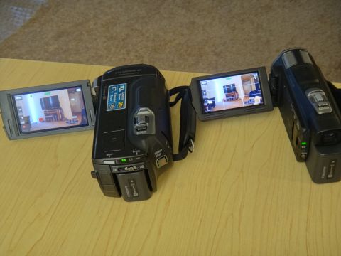 1993 Ford Taurus - Two camcorders are displayed on a wooden surface, with one's LCD screen open and active.