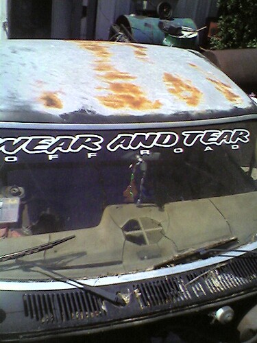 1989 Ford Bronco - Vehicle hood shows significant rust damage and has an "OFFROAD" sticker on the windshield.