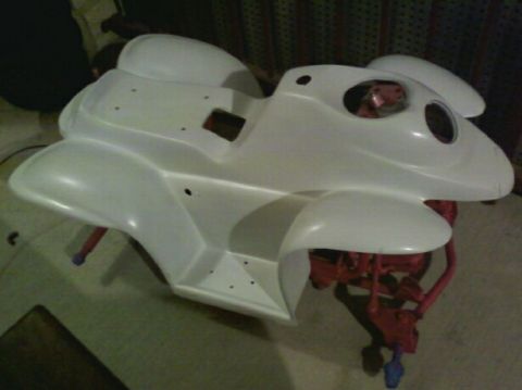 1989 Ford Bronco - A white motorcycle fairing is mounted on a red stand, awaiting assembly or painting.