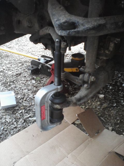 1989 Ford Bronco - A ball joint separator tool is used on a vehicle's suspension system.