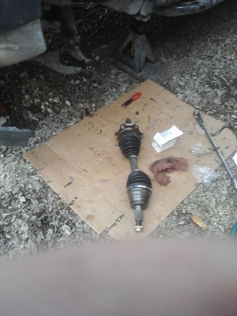 1989 Ford Bronco - A CV axle is laid out on cardboard with tools, suggesting a vehicle repair in progress.
