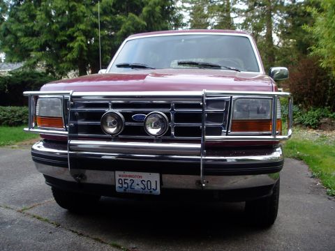1993 Ford Bronco - A maroon Ford Bronco with a chrome bull bar and fog lights is parked on a driveway.