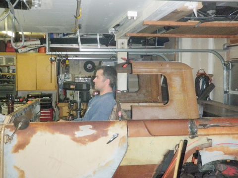 1961 International Scout 800 - A man sits in the driver's seat of a vintage truck, surrounded by tools and garage equipment.