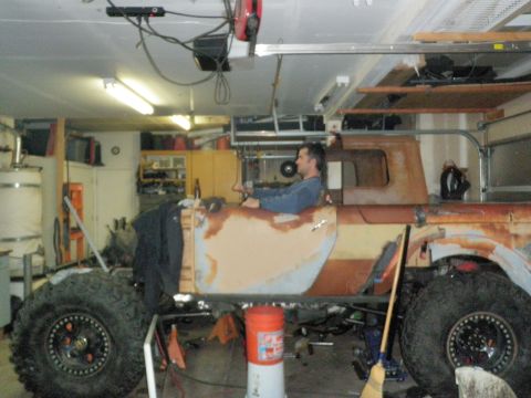 1961 International Scout 800 - A heavily modified vehicle, possibly a custom build, sits in a garage with a person inside.