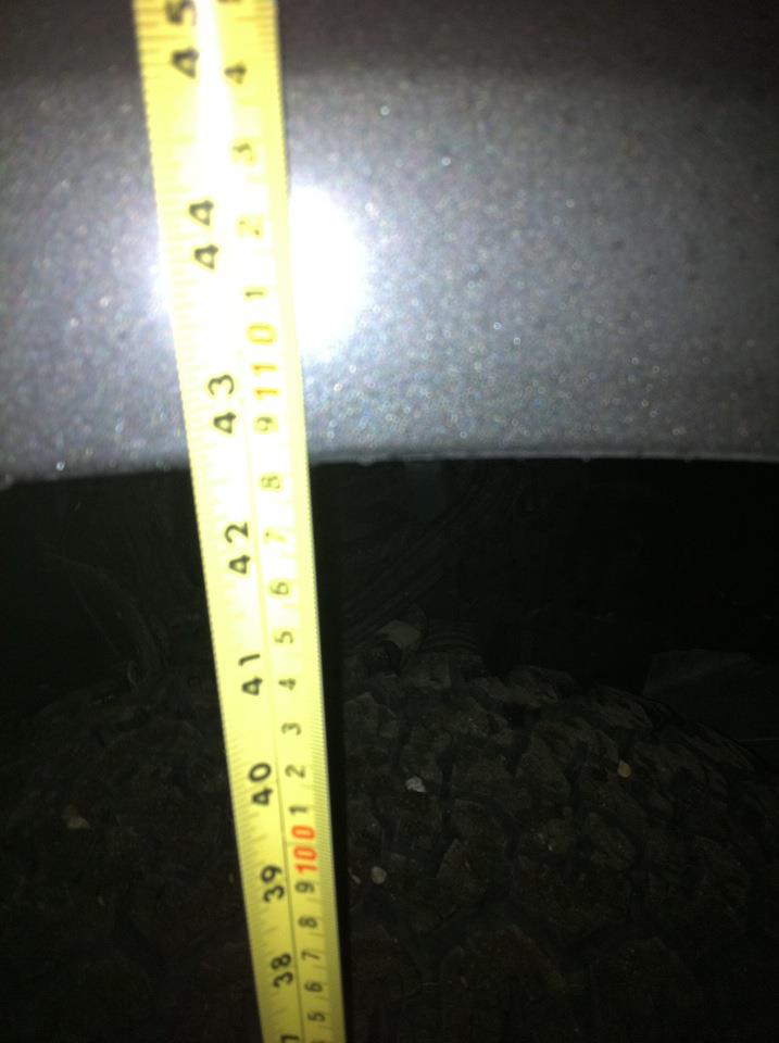 Yellow measuring tape showing approximately 40-45 inches against a dark gray vehicle body panel