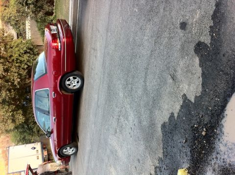 1998 Ford Crown Victoria - Side view of a red 1998 Ford Crown Victoria parked on a paved surface.