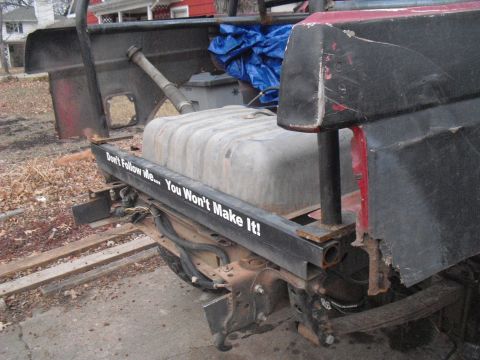 1986 Ford Bronco - This truck features a prominent aftermarket fuel tank and a humorous bumper sticker.
