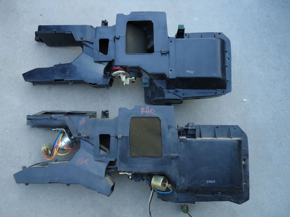 Two black HVAC heater core housings with wiring on concrete floor