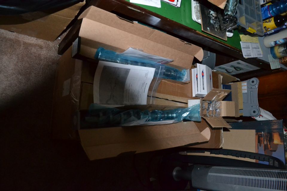 Open cardboard boxes of new shock absorbers and parts on a workbench