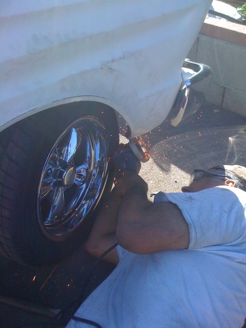 1964 Ford Ranchero - A man uses an angle grinder on the rear fender of a 1964 Ford Ranchero, which has chrome wheels.