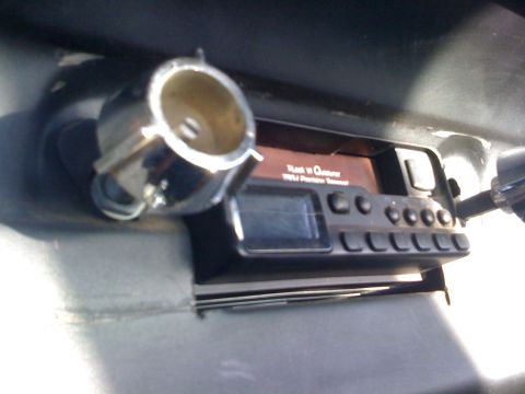 1964 Ford Ranchero - A car stereo with a digital display and multiple buttons is visible, along with a chrome cup holder mounted nearby.