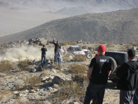 1996 Ford Bronco - Spectators watch as a buggy races through a dusty, rocky desert terrain.