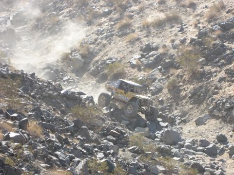 1996 Ford Bronco - An off-road vehicle navigates a challenging rocky terrain, kicking up dust.