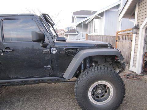 2008 Jeep Wrangler - Side view of a black Jeep Wrangler, showing the front fender, large tire, and a "JK" badge on the door.
