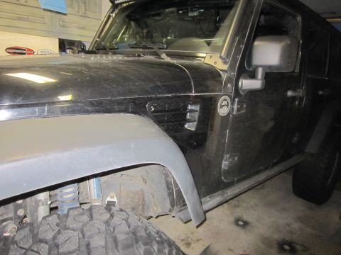 2008 Jeep Wrangler - Close-up of a black Jeep Wrangler's front fender and driver's side door, revealing suspension components.