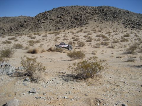 1996 Ford Bronco - A custom off-road buggy navigates a dusty desert terrain under a clear blue sky.