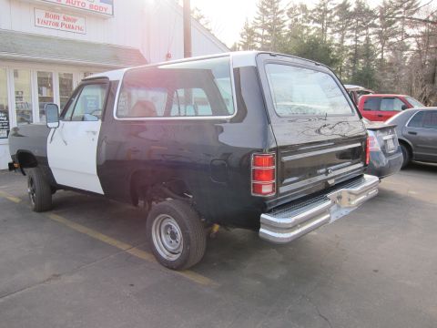 1987 Dodge 1500 - A Dodge Ramcharger with mismatched paint is parked in front of a body shop.