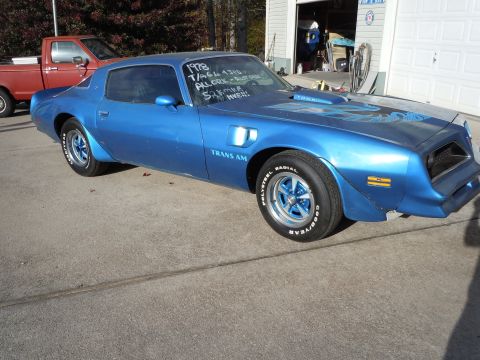 1982 Chevrolet Camaro - A blue 1978 Pontiac Trans Am is parked outside a garage, with a red pickup truck visible in the background.