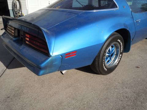 1982 Chevrolet Camaro - The rear of a blue Pontiac Trans Am is shown, its distinctive taillights and spoiler.