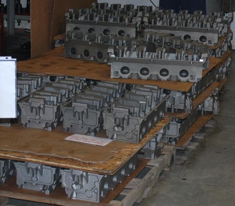 1969 Ford Fairlane - Numerous engine cylinder heads are stacked on pallets in a warehouse setting.