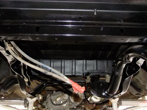 1995 Ford Bronco - The underside of a vehicle is shown, with focus on the frame, exhaust, and drivetrain components.