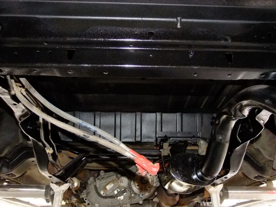 Underside of a vehicle with black painted frame, exhaust pipe, and transmission components