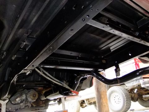 1995 Ford Bronco - The undercarriage of a vehicle shows its frame, exhaust system, and drivetrain components.