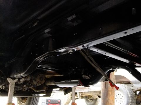 1995 Ford Bronco - The undercarriage of a vehicle is shown, supported by jack stands during maintenance.
