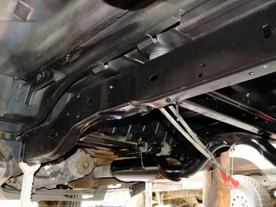 Undercarriage of a 1990s Ford Bronco showing frame, exhaust, and drivetrain components