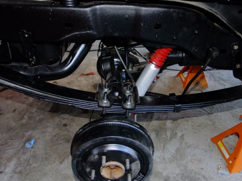 1995 Ford Bronco - Close-up view of the rear axle, leaf springs, and shock absorber assembly, likely during maintenance or restoration.