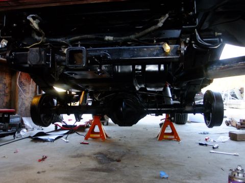 1995 Ford Bronco - The rear chassis and suspension components are visible while the vehicle is elevated on jack stands.