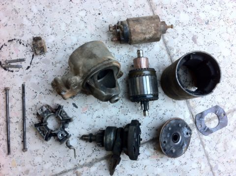 1998 Ford Crown Victoria - Disassembled starter motor parts are spread out on a tiled floor, ready for inspection or repair.
