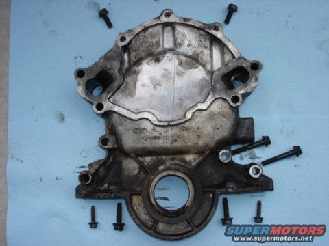 1987 Ford Bronco - A disassembled engine timing cover is laid out with bolts on a blue shop towel.