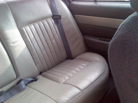 1999 Ford Crown Victoria - The interior of a car shows the rear passenger seat and door panel, with a watermark at the bottom right.