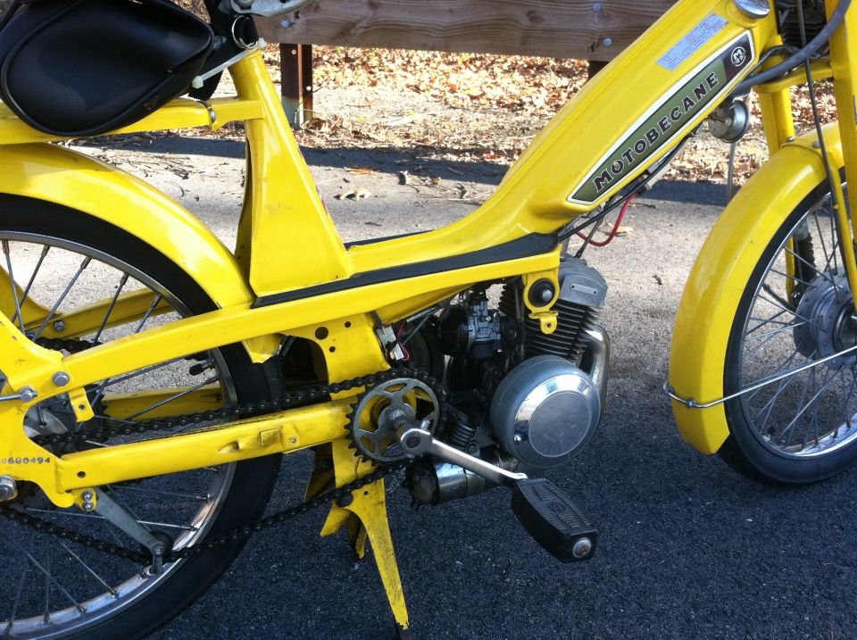 Yellow Motobecane moped side view, showing engine and chain
