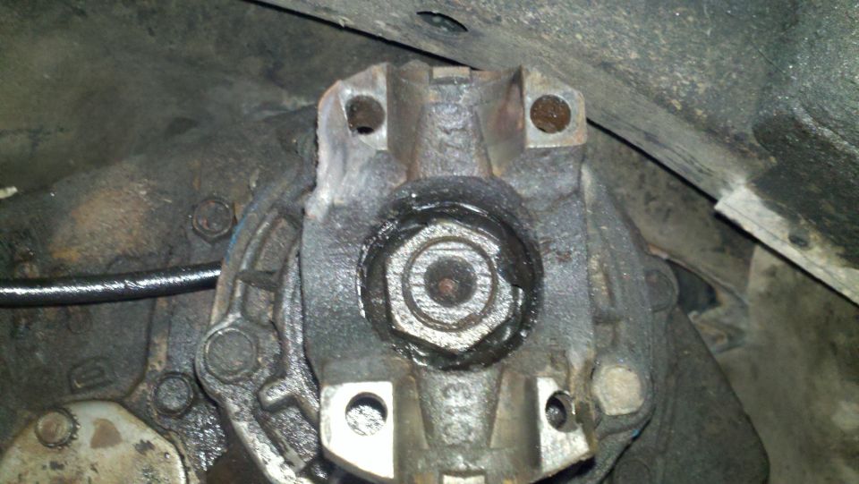 Close-up of a driveshaft flange with a U-joint attached, showing grease and bolts