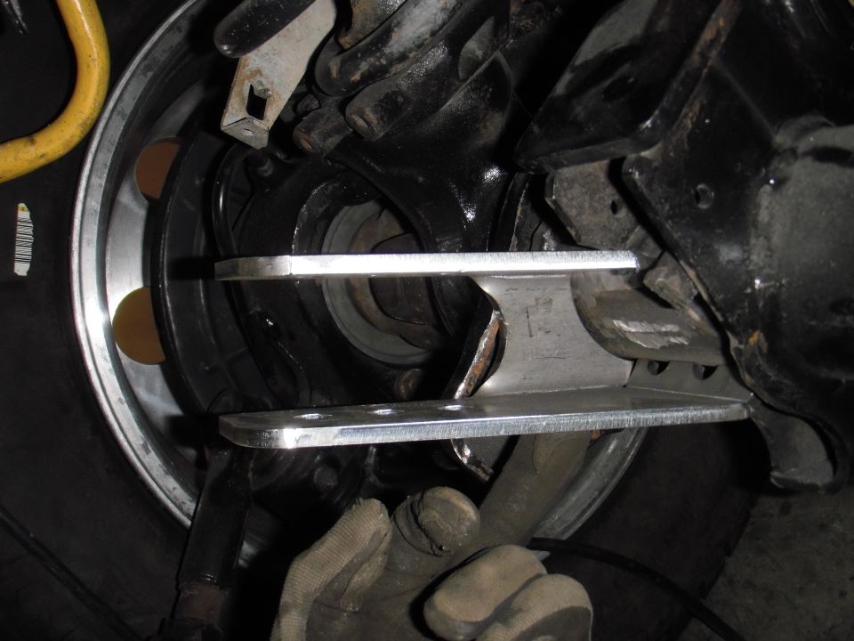 Bare metal multi-hole bracket welded to black axle near knuckle during fabrication on a Ford Bronco
