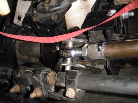 1995 Ford Bronco - Undercarriage view of a vehicle's steering and suspension system, with visible metal components and a red strap.
