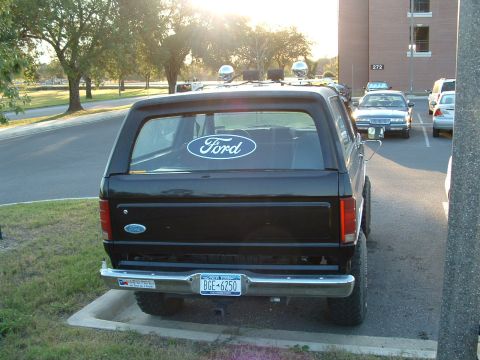 1985 Ford Bronco - Rear view of a 1985 Ford Bronco parked in a lot, showing the Ford logo and license plate.