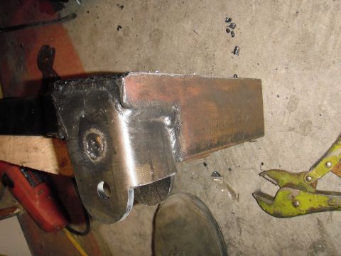 1995 Ford Bronco - A close-up view of a welded metal bracket, likely a vehicle part, on a concrete floor.