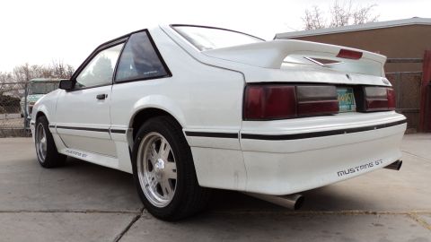 1989 Ford Mustang - This white Ford Mustang GT features a distinctive rear spoiler and dual exhaust pipes.