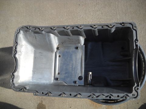 1992 Ford Explorer - An oil pan is shown from above, with visible bolts and a metal plate attached to its interior.
