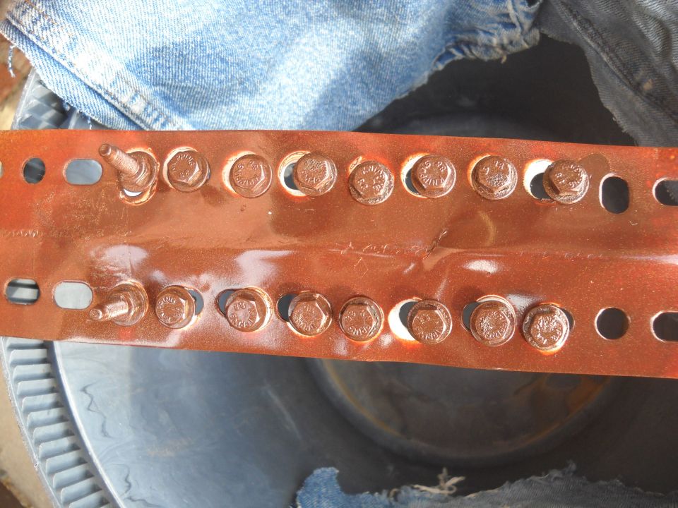 Metal bracket with two rows of bolts, partially covered by denim