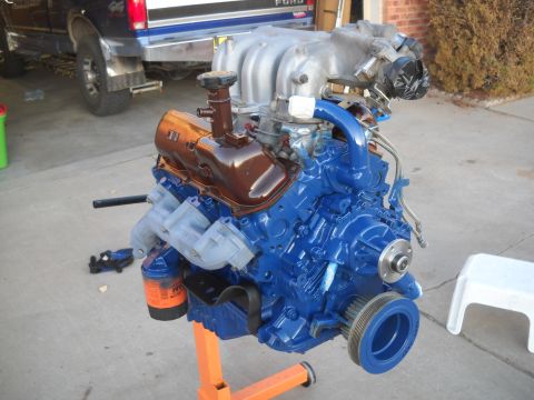 1992 Ford Explorer - A blue engine is mounted on an orange stand, with a Ford truck visible in the background.