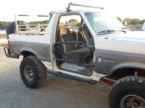 1991 Ford Bronco - This modified Ford Bronco features an open driver's door, revealing its interior and roll cage.